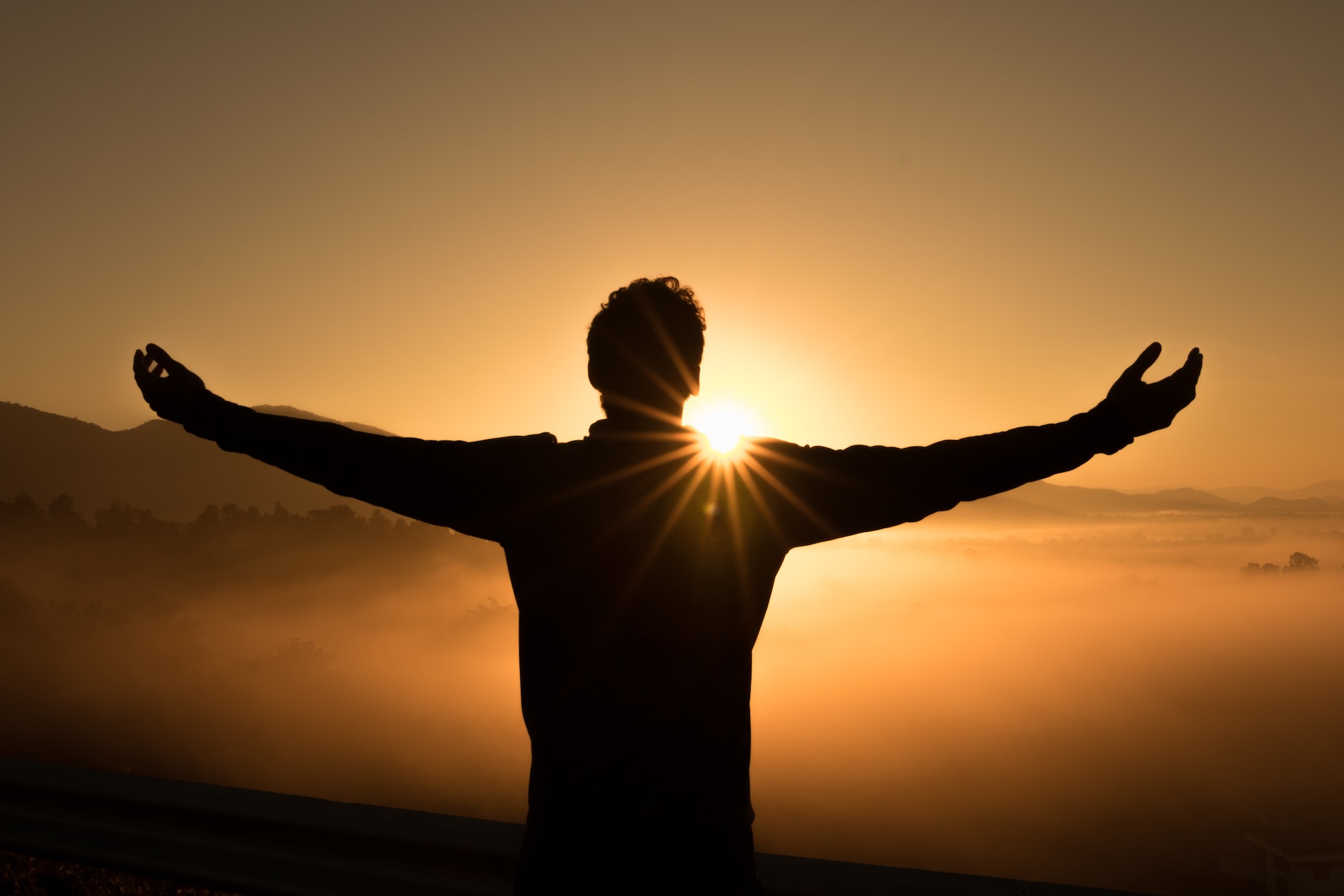 Man with Arms Wide Open Facing Towards the Sun